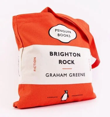 An orange and white canvas tote bag designed like the Penguin Books 'Brighton Rock' book cover, featuring the author Graham Greene and a penguin logo.